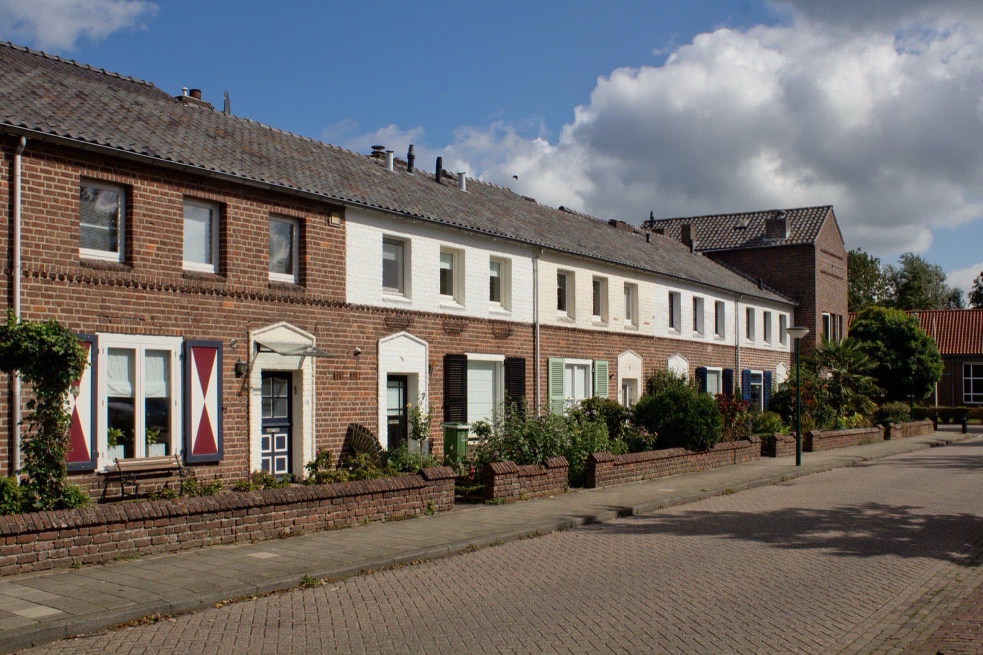 Rij rijtjeshuizen uit de jaren vijftig met rode en witte gevels en gekleurde luiken aan het Bikkelkampplein in Grave, gemeente Land van Cuijk.