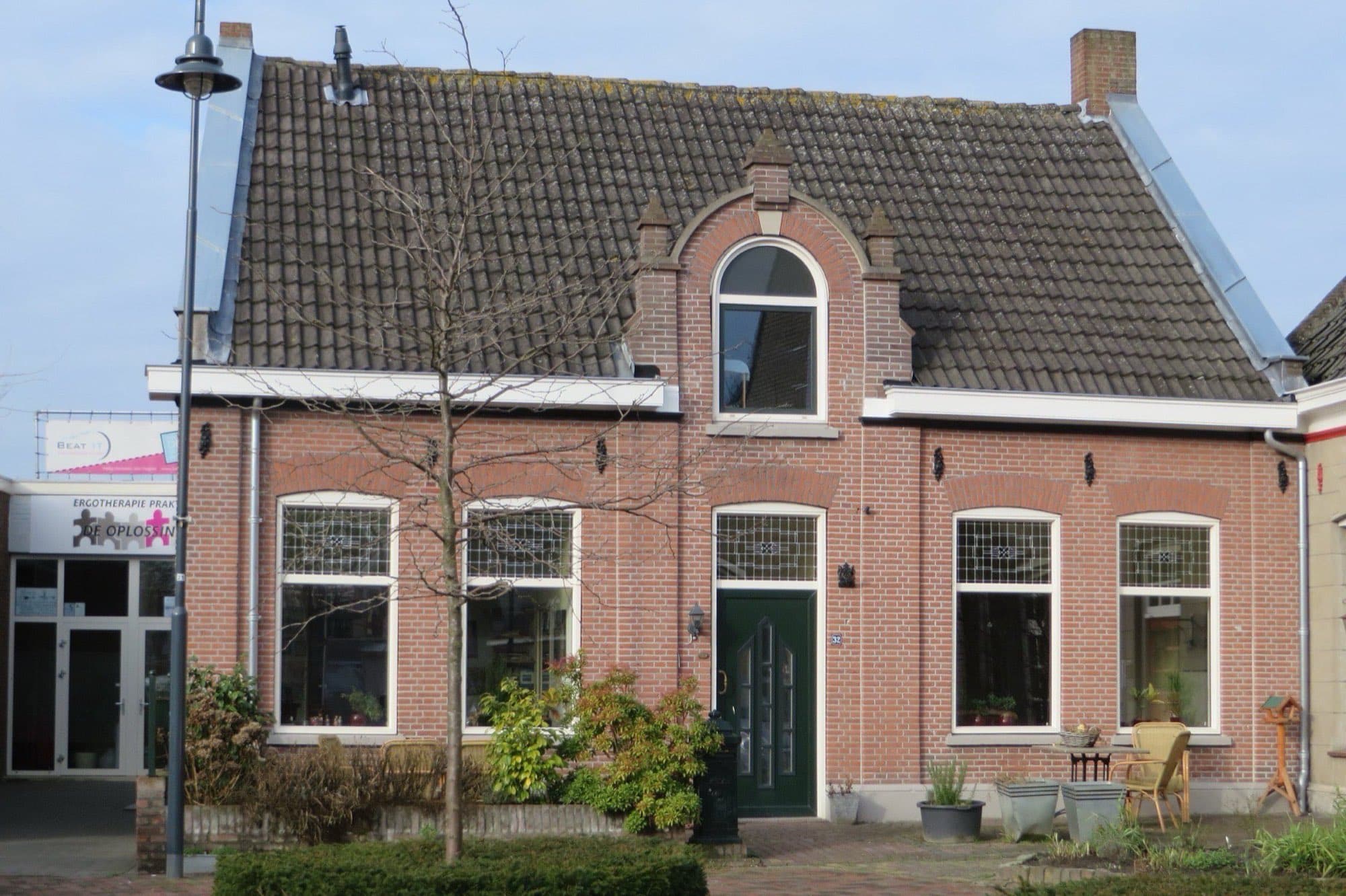 Bakstenen woonhuis met een rondboogvenster boven de voordeur, witte kozijnen en een grijs pannendak aan het Heilig Hartplein in Veghel, gemeente Meierijstad.