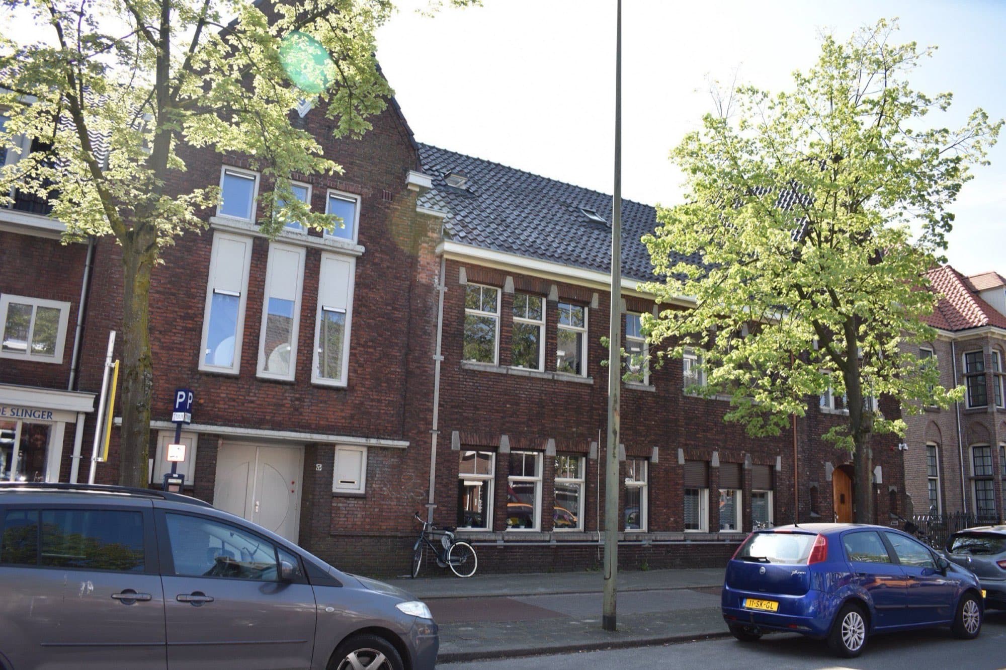 Bakstenen woningen in jaren-dertigstijl met erkers en dakkapellen aan de Jan Schöfferlaan in de Bossche wijk De Muntel, onder jonge lindes.