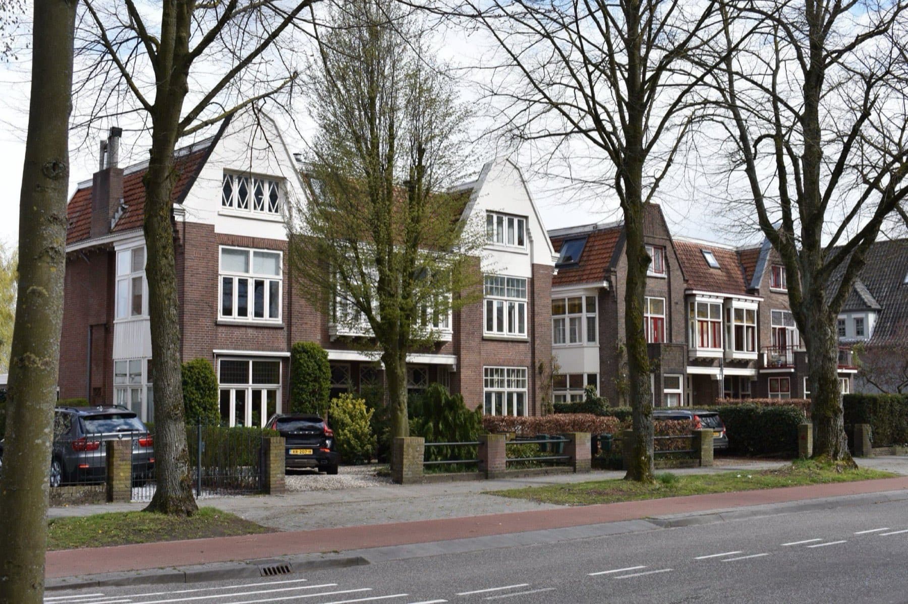Rij bakstenen villa's in jaren-dertigstijl aan de Bosscheweg in Vught, met kale laanbomen op een voorjaarsdag.