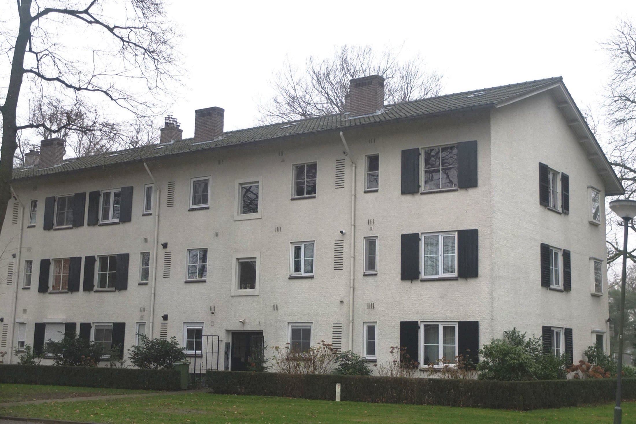 Wit gepleisterd appartementengebouw van drie lagen met donkere luiken aan Park Reeburg in Vught, in de winter.